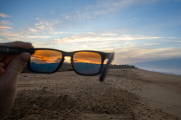 view of the sunrise on a beach partially through polarised sunglasses