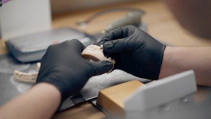 close up professional laboratory for the production of dental protoses veneers and crowns a specialist adjusts a crown to the shape of a person's jaw gums professional equipment