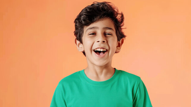 Joyful Colombian pre-teen boy with wavy hair wearing green on orange background
