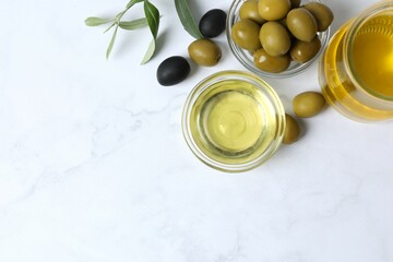 Bowl of fresh olive oil and olives with leaves on white background