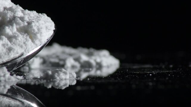 Powder of cocaine in a spoon over a crystal
