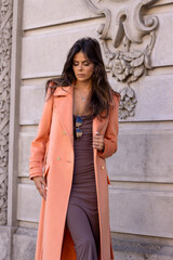 Street fashion, gorgeous woman in a coat poses on the street on an autumn day