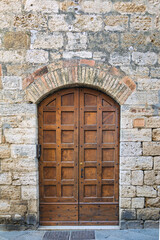 Elegant old double door entrance with metal forged rivets of brick pastel building in Europe. Vintage wooden doorway of ancient stone house. Simple light brown wood door. Architecture in Italy.