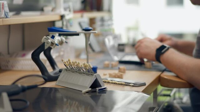professional laboratory for the production of dental protoses veneers and crowns a specialist adjusts a crown to the shape of a person's jaw gums professional equipment