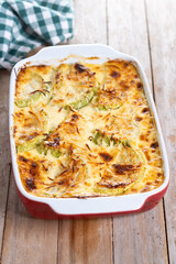 Casserole with cheese and gratin zucchini on wooden table