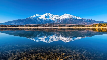 Naklejka premium Snow-Capped Mountains Reflected in a Crystal Clear Lake Under a Bright Blue Sky