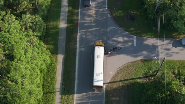 Students boarding school bus at bus stop before going to lessons standing in line. Coming back to school in new educational year semester. Public school transportation in the USA.