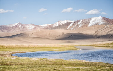 High mountain landscape panorama, a river in the mountains flows in a mountain valley among green meadows against the backdrop of mountains, landscape in the Pamir Mountains for background