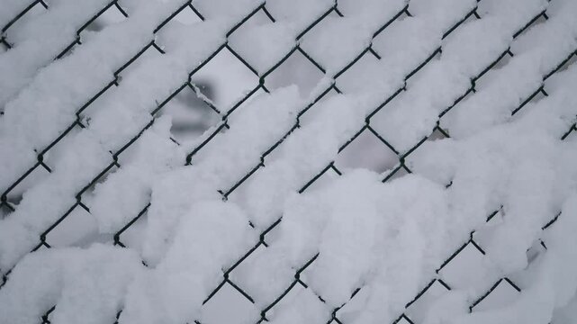 Snow-covered chain-link fence, focusing on the geometric patterns created by the snow buildup