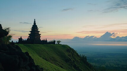 Silhouette of an ancient temple on a hilltop at sunrise.
