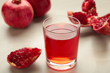 Natural, fresh pomegranate juice in a glass with pomegranates on light background. Top view