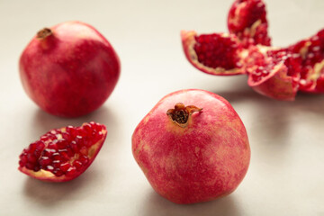 A whole pomegranate and a half-cut pomegranate with seeds on light background. Top view