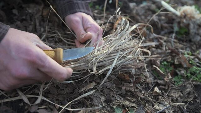 A man uses a knife and firestarter to create sparks and ignite a fire in dry grass. This survival technique captures the essence of outdoor skills and wilderness preparedness
