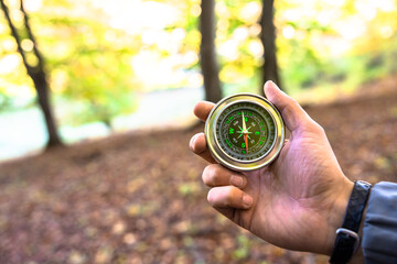 Naklejka premium Compass in man's hands, autumn forest, travel