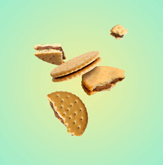 Tasty broken sandwich cookies in air on turquoise gradient background