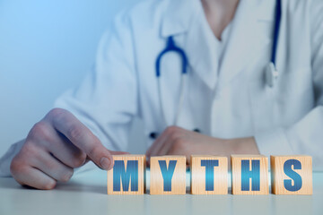Medical myths. Doctor making word of wooden cubes with letters, closeup