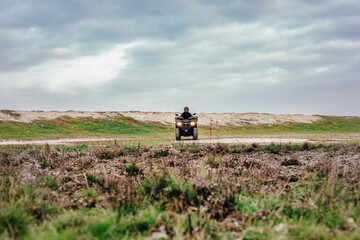 Fototapeta premium Rugged quad biker on dirt path under cloudy sky