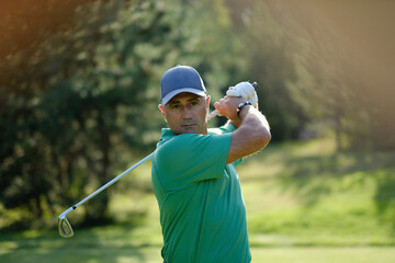 Golfer swings club on a sunny afternoon at a scenic golf course in the countryside concept