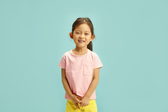 Smiling Chinese appearanceed Child Girl in Casual Summer Outfit Cheerful Stands Over Blue Isolated, Studio Portrait