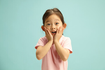 Surprised Child Korean Kid Girl Amazement Holding Cheeks Looking to Camera Standing on Blue Isolated
