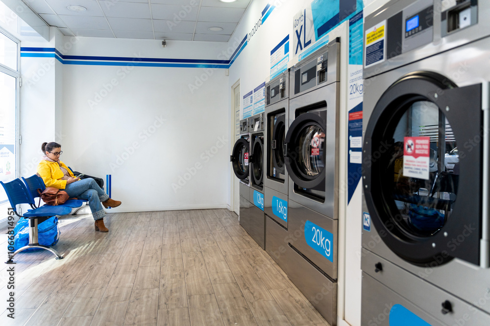 Wall mural Woman waiting to wash her clothes in a laundromat