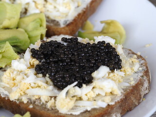 Open-Faced Sandwich with Black Caviar, Eggs, and Avocado on White Background