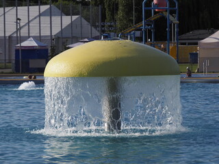 Yellow Dome Fountain in Park with Waterfall and Trees in Background