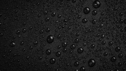 Water drops on a black background. Textured surface for design or text. Top view. Free space.