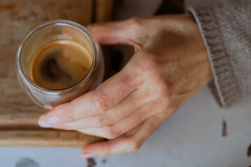 Close-up image of a glass cup of coffee held in woman hand. Caffeine and restaurant for cappuccino. Customer, hospitality for female person, morning and barista for breakfast. Hand-roasted coffee.