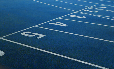 Blue running tracks with white lane markings and numbered start lines.