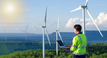 A young engineer is monitoring and inspecting a wind turbine in the field using a digital tablet,...