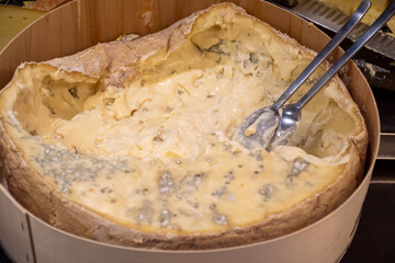 Italian food, buttery or firm blue cheese made from cow milk in Gorgonzola, Milan, Italy in large wooden box on Italian farmers market
