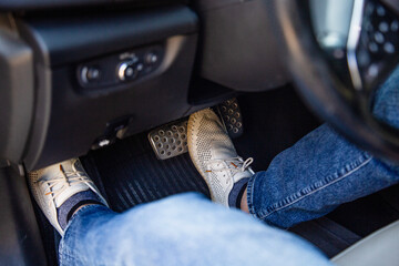 Close-up of driver's feet pressing the brake pedal in car