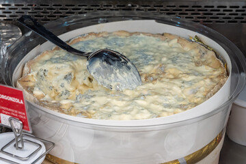 Italian food, buttery or firm blue cheese made from cow milk in Gorgonzola, Milan, Italy in large box on Italian farmers market