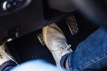 Close-up of driver's feet pressing the brake pedal in car