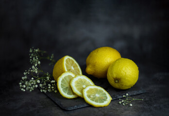 still life of lemons and white flowers on the vintage table on a dark background