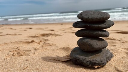 Stacked stones on a beach with ocean waves.