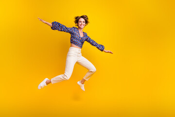 Full body length photo of young cheerful funny girl jumping flying wings arms tourist on vacation isolated over yellow color background