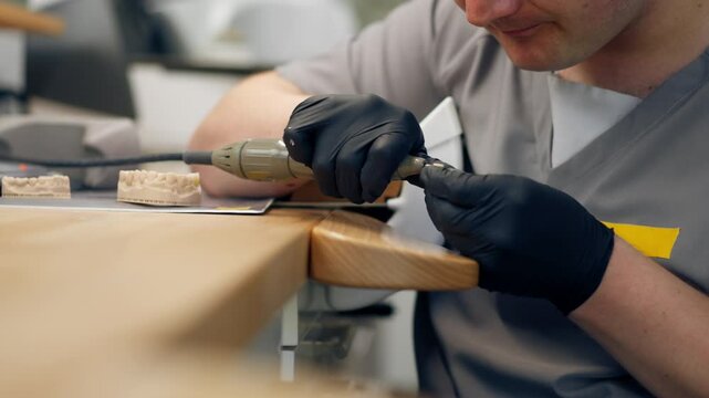 close up professional laboratory for the production of dental protoses veneers and crowns a specialist adjusts a crown to the shape of a person's jaw gums professional equipment