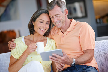 Sofa, mature couple and hug with tablet for online joke, comedy film and streaming on website....