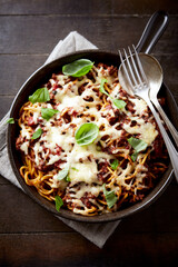 Baked  spaghetti pasta with mozzarella cheese. Wooden background. Top view.
