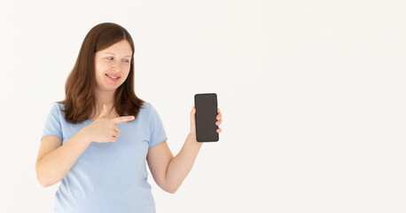Naklejka premium Close up portrait of a smiling woman showing and pointing at blank screen mobile phone while standing isolated over white background