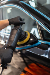 Professional man holding polishing tool and polishing car after painting. Varnish care and scratch removal. Detailing