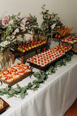 A variety of appetizers, including fruit balls on skewers. The table is decorated with greenery and flowers.
