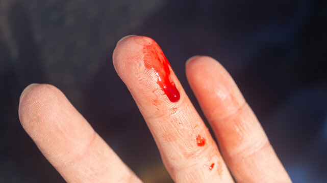 Finger in blood. Bloody finger. Close-up of a drop of blood running down a finger