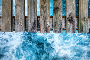 Fototapeta premium Old wooden suspended bridge over blue river