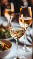 Obraz premium Elegant white wine glasses at a festive dinner table with gourmet dishes.