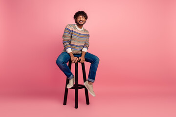 Full size portrait of nice young man sit stool smile isolated on pink color background