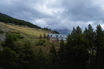Fototapeta premium Beautiful wooded landscape in the mountains of northern Spain with a stone house and black slate roof. The day is cloudy, gray and rainy and gives the image a dramatic appearance