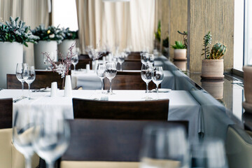 The restaurant features a stylish and contemporary interior complete with elegant table settings and vibrant plants.